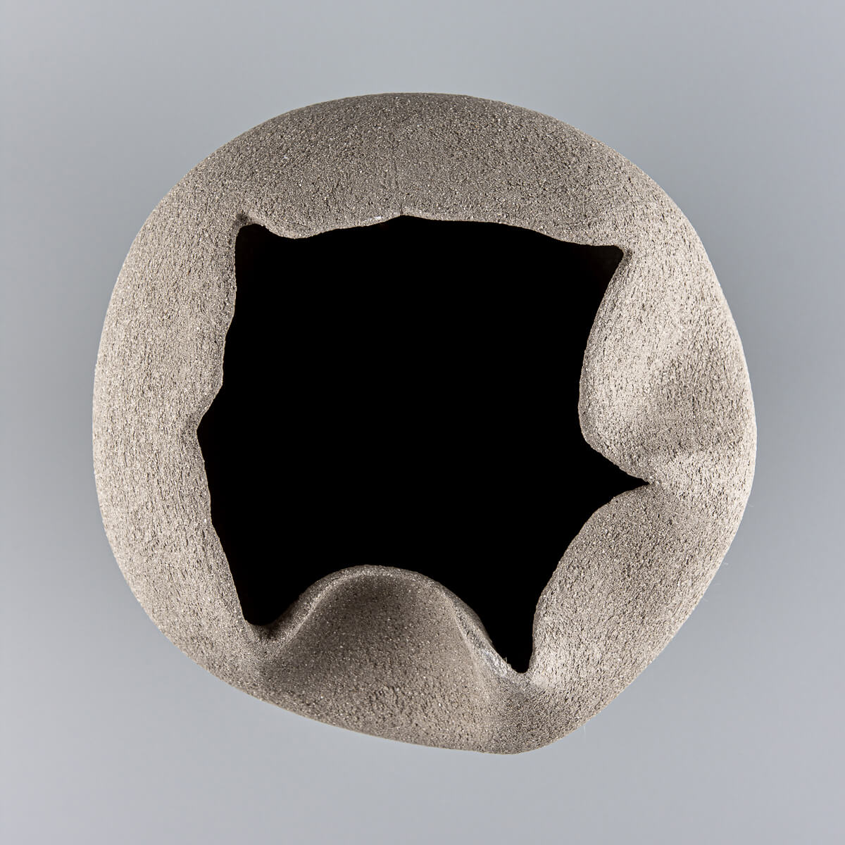 Unglazed sculptural pottery vase with textured surface for boutique hotel and home decor.