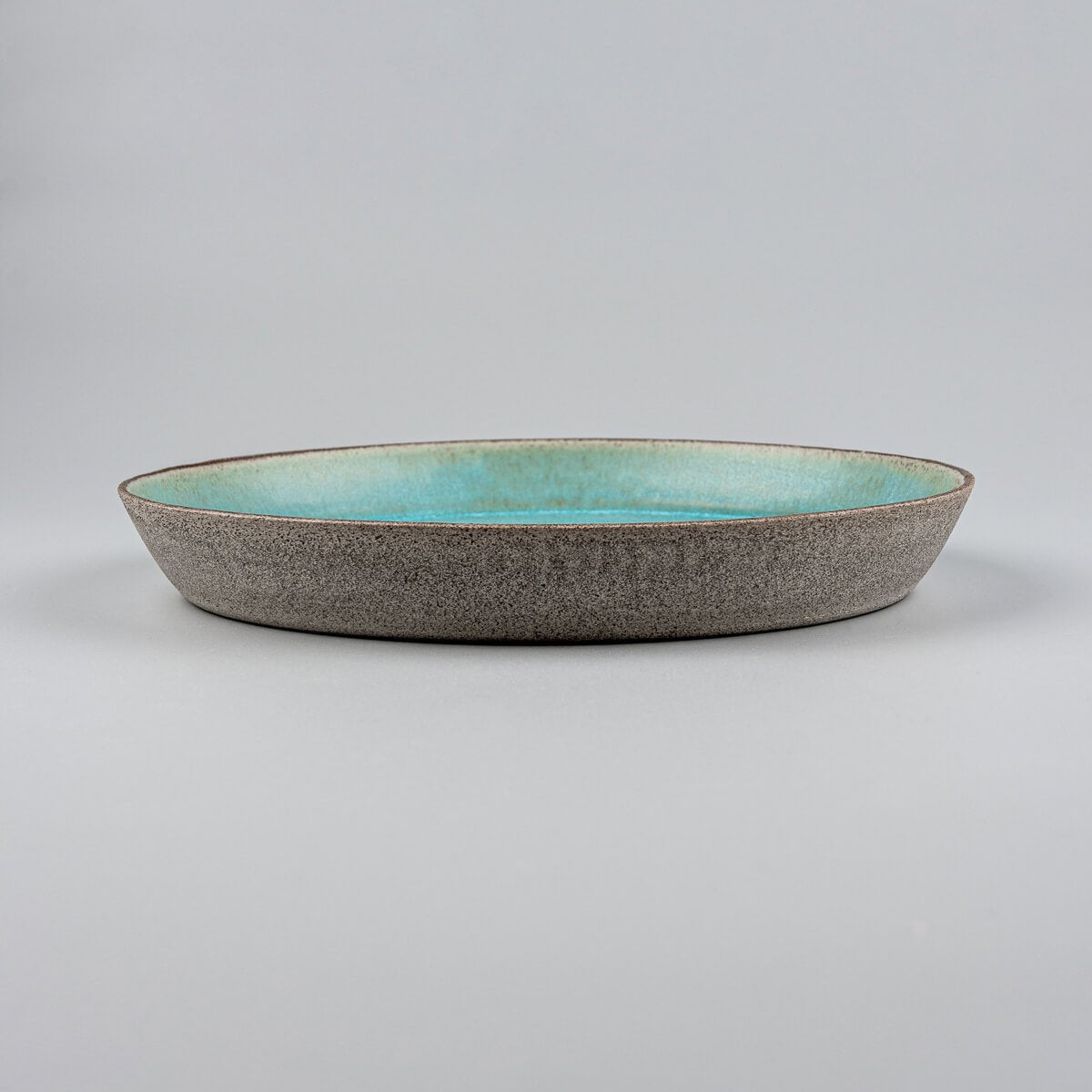 Side view of handcrafted ceramic plate with natural dark stoneware clay and elegant form.