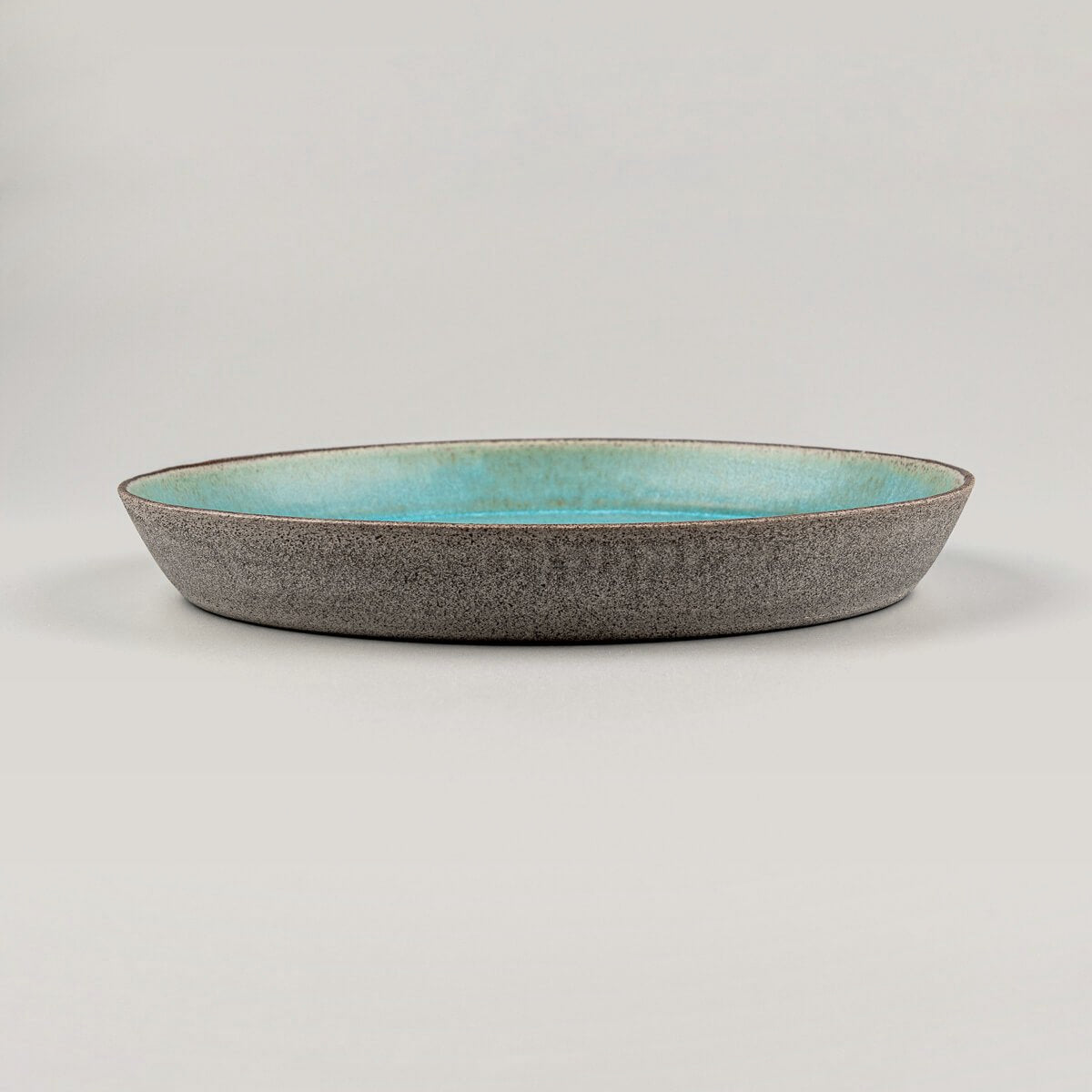 Side view of handcrafted ceramic plate with natural dark stoneware clay and elegant form.