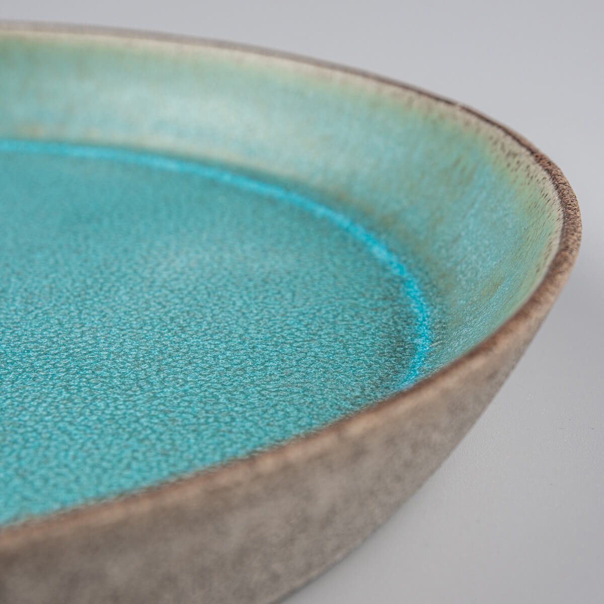 Premium ceramic plate with unique contrast between glazed interior and raw clay exterior.
