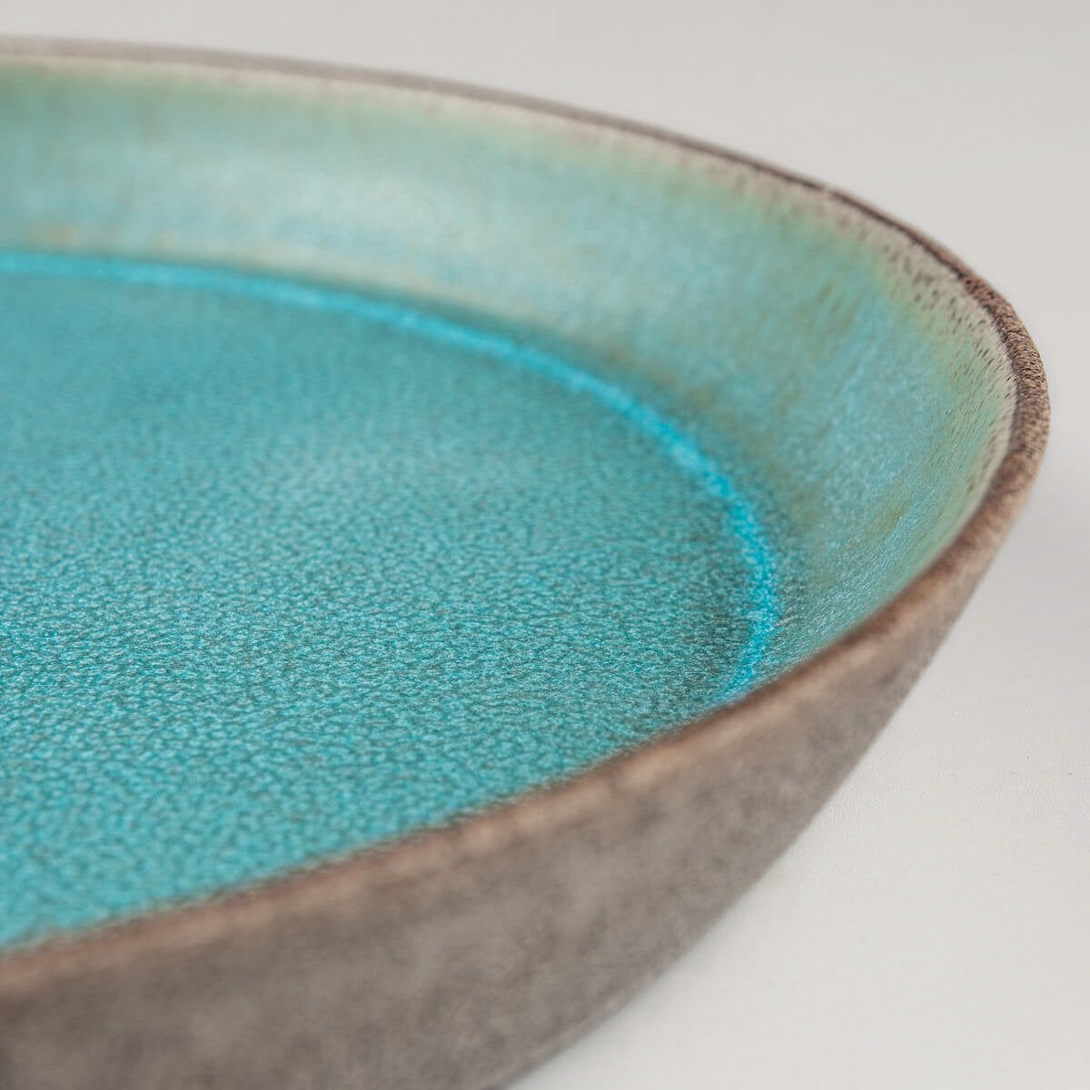 Premium ceramic plate with unique contrast between glazed interior and raw clay exterior.