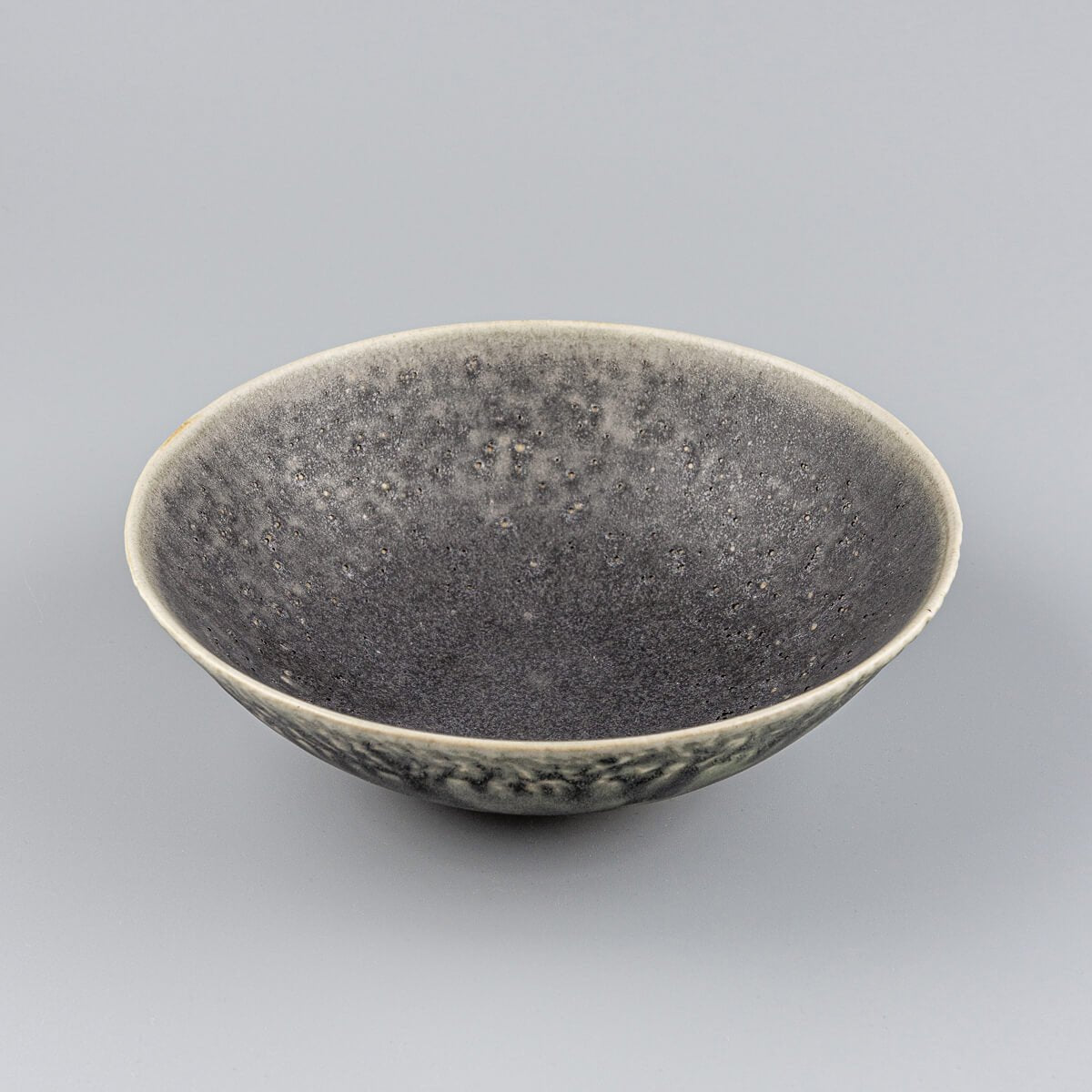 Angled profile of custom ceramic bowl highlighting textured green glaze and artisan form.