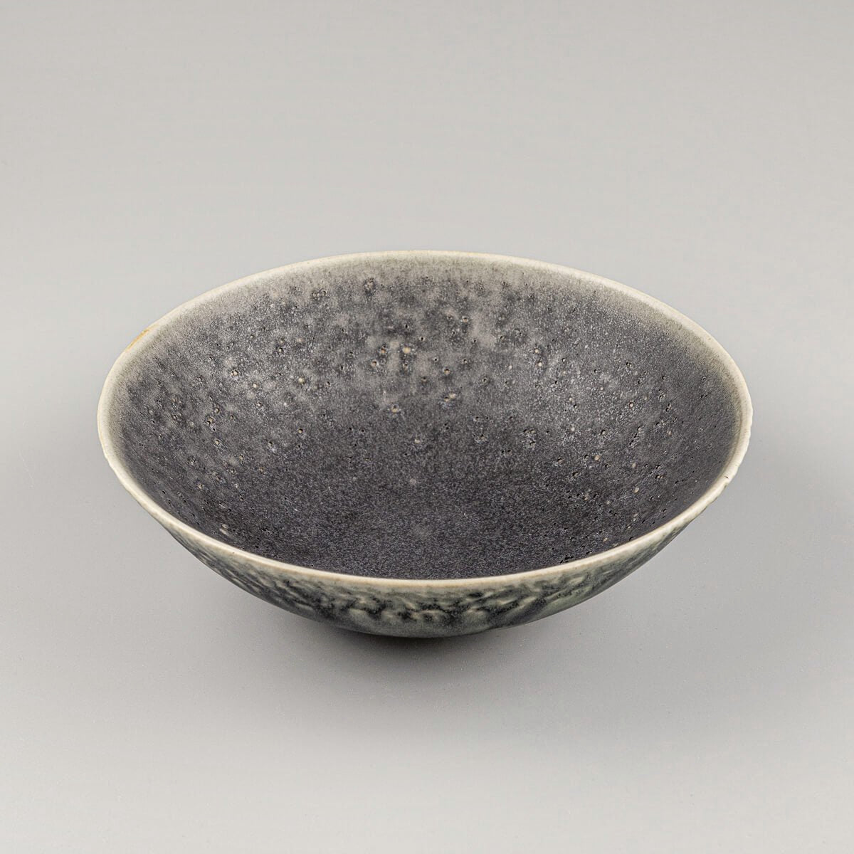 Angled profile of custom ceramic bowl highlighting textured green glaze and artisan form.