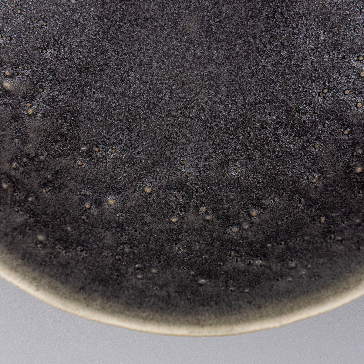 Detailed side texture of handcrafted ceramic bowl with forest green matte finish.