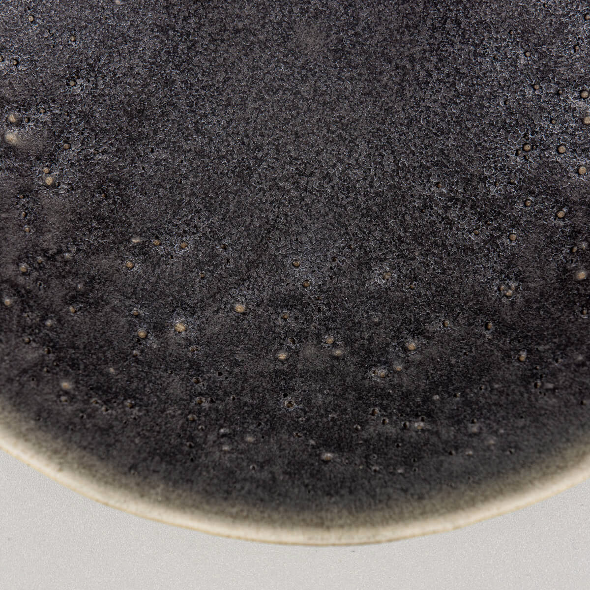 Detailed side texture of handcrafted ceramic bowl with forest green matte finish.