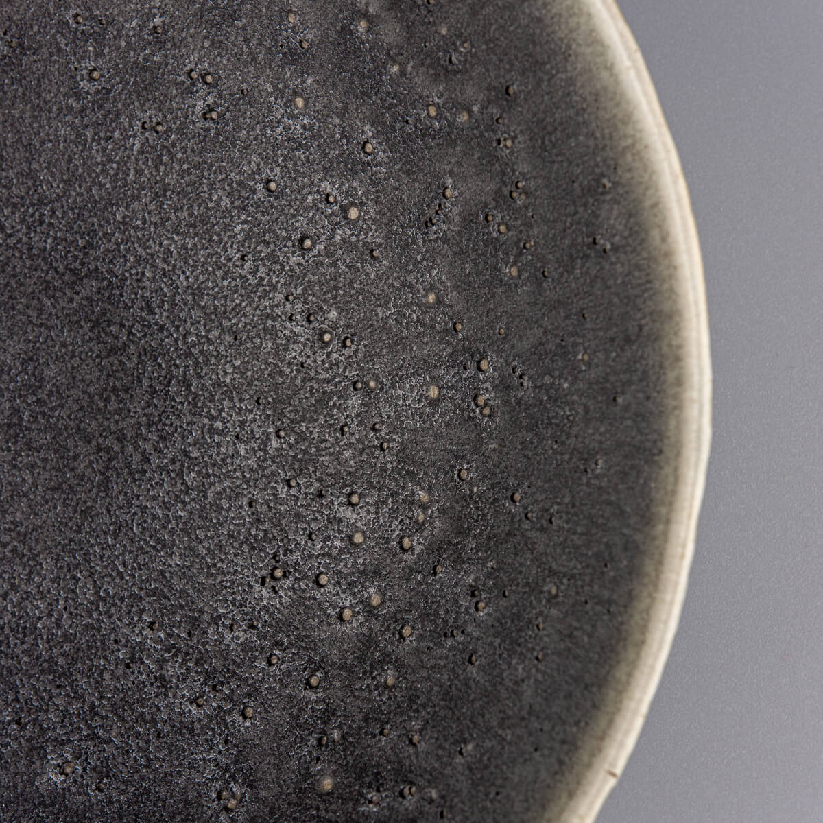 Zoomed corner view of textured handmade ceramic bowl with smooth interior surface.