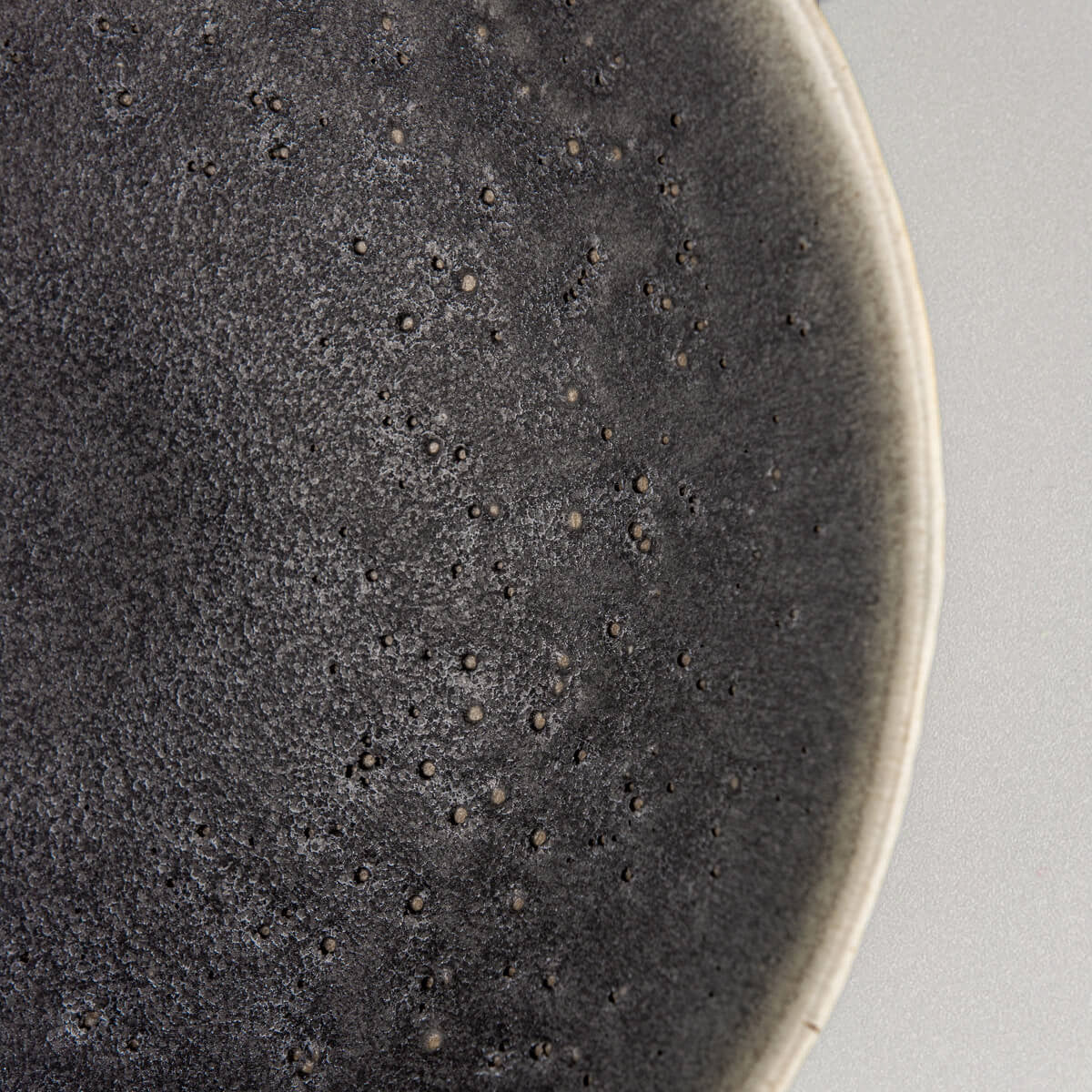 Zoomed corner view of textured handmade ceramic bowl with smooth interior surface.