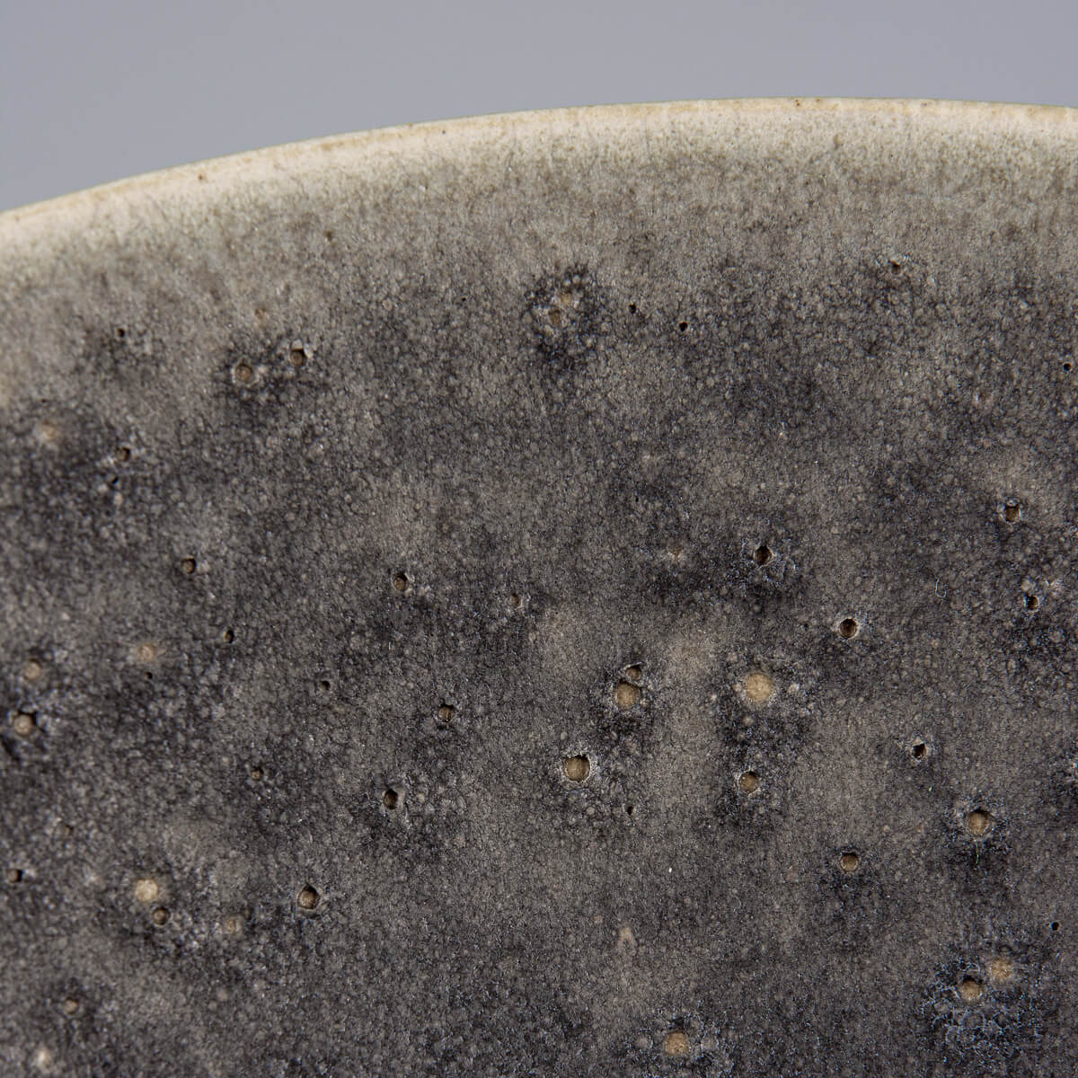 Carved detail on rim of matte-glazed ceramic bowl for fine dining presentation.