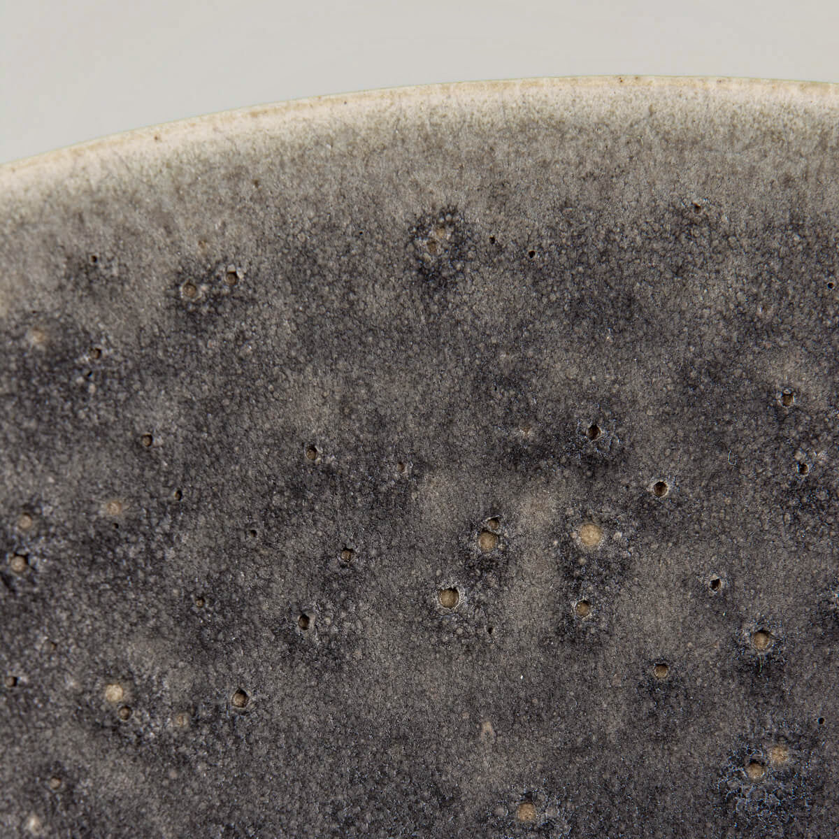 Carved detail on rim of matte-glazed ceramic bowl for fine dining presentation.