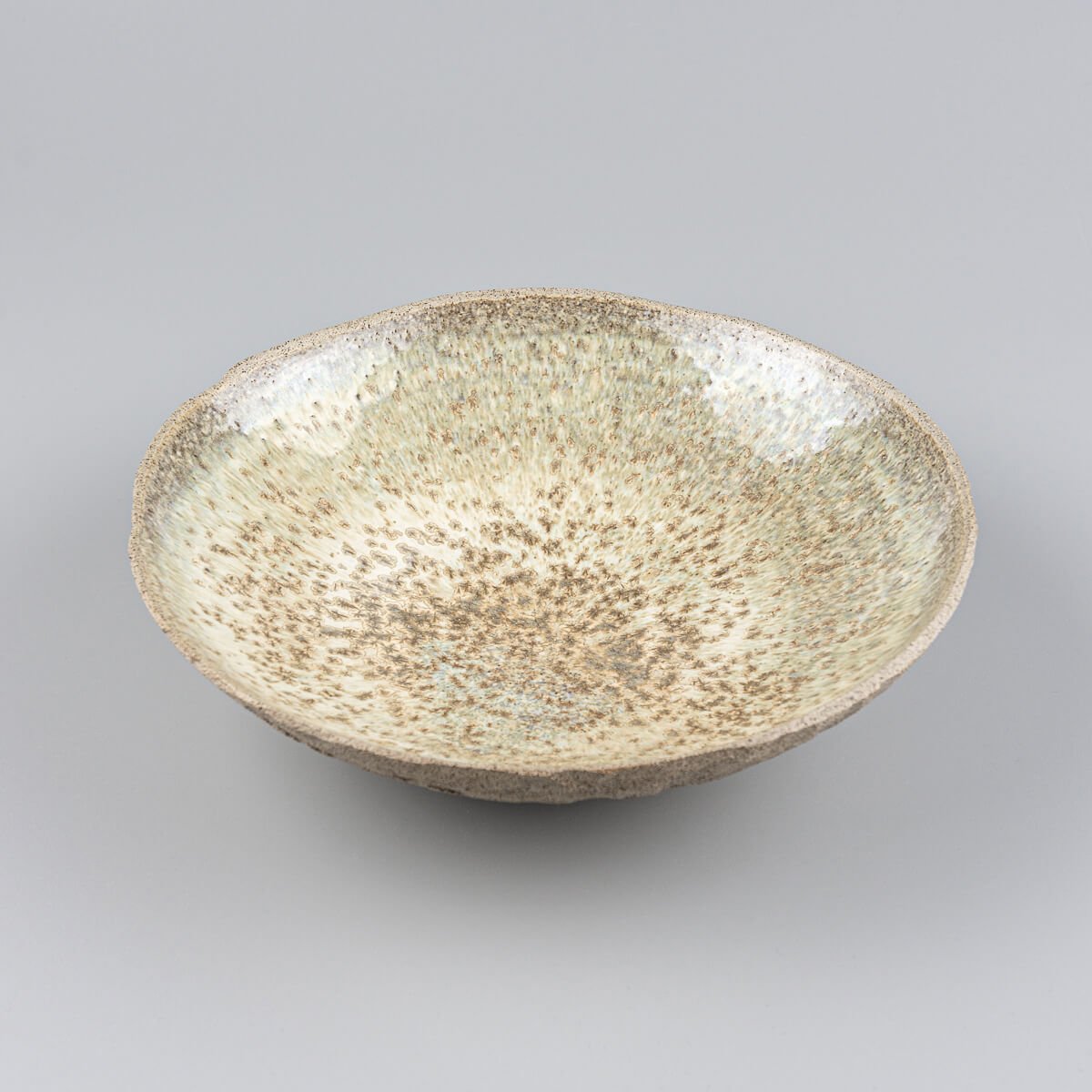 Hand-holding view of custom handmade ceramic plate, highlighting scale and fine craftsmanship.