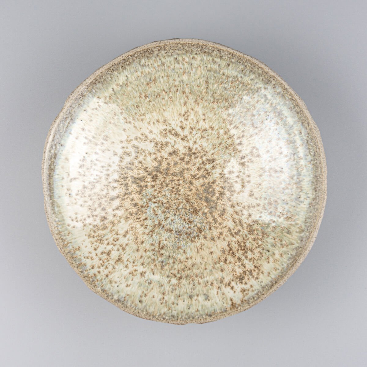 Handmade ceramic plate with carved stoneware exterior and glossy glazed interior for luxury table settings.