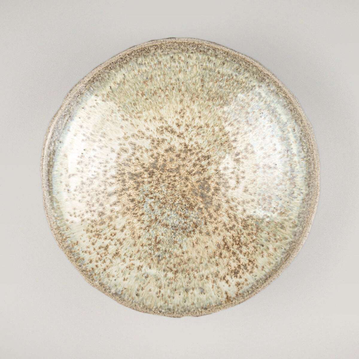 Handmade ceramic plate with carved stoneware exterior and glossy glazed interior for luxury table settings.