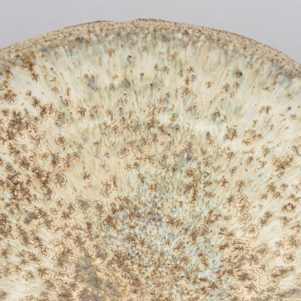 Angled image showing deep bowl form and hand-carved exterior of fine ceramic plate.