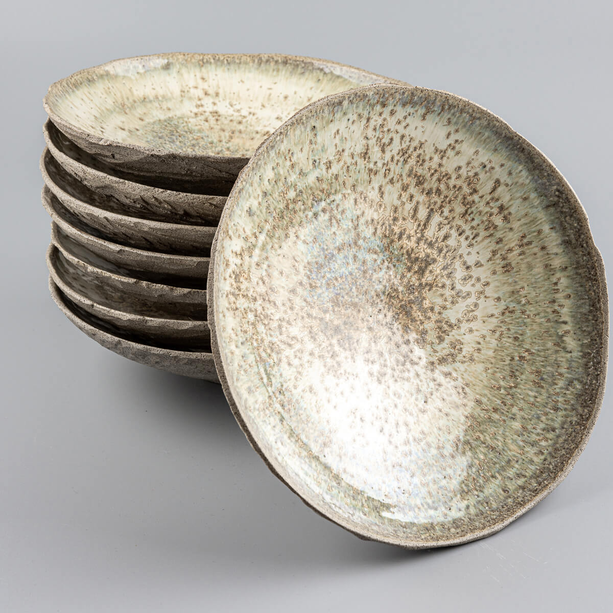 Stacked artisanal ceramic plates showcasing uniform hand-thrown craftsmanship.