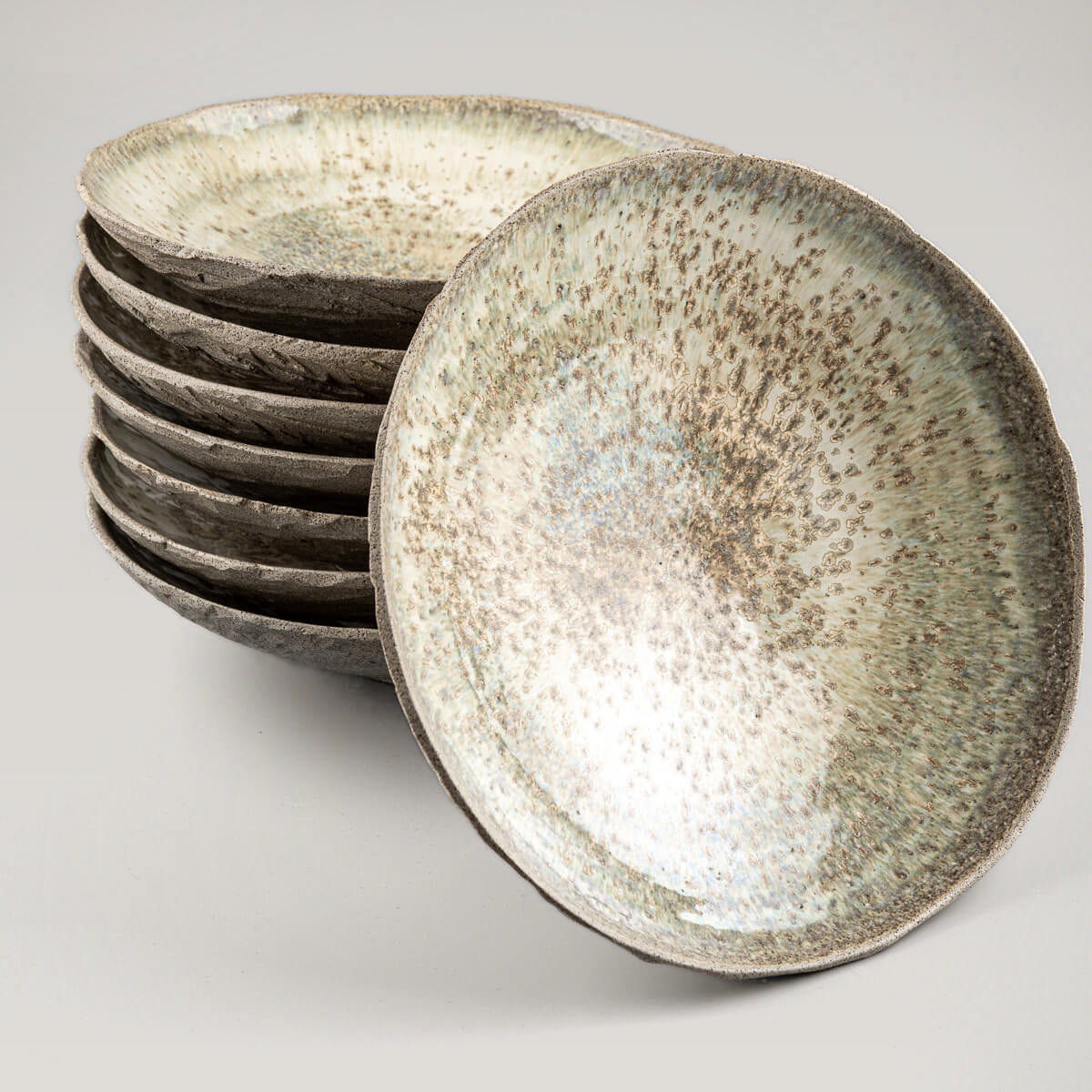 Stacked artisanal ceramic plates showcasing uniform hand-thrown craftsmanship.