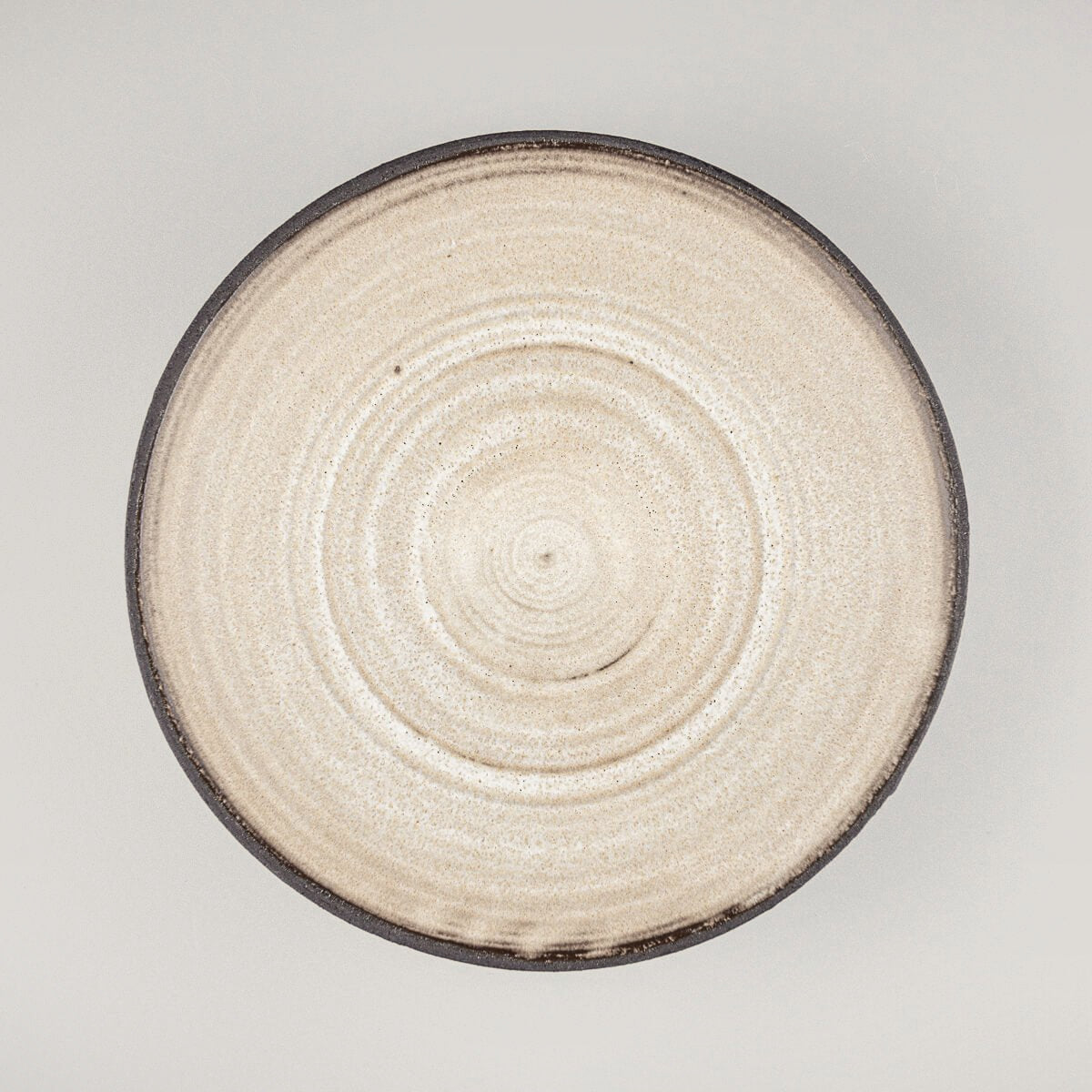 Top view of handmade ceramic plate with matte white interior and wheel-thrown texture.