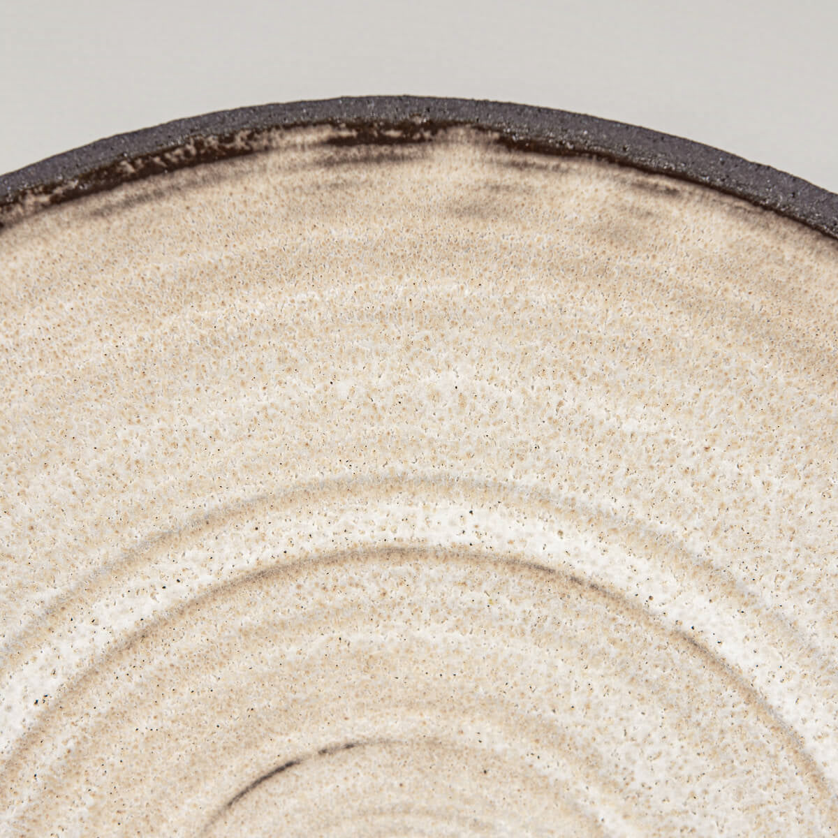 Close-up of wheel-thrown grooves and matte glaze finish inside artisan plate.