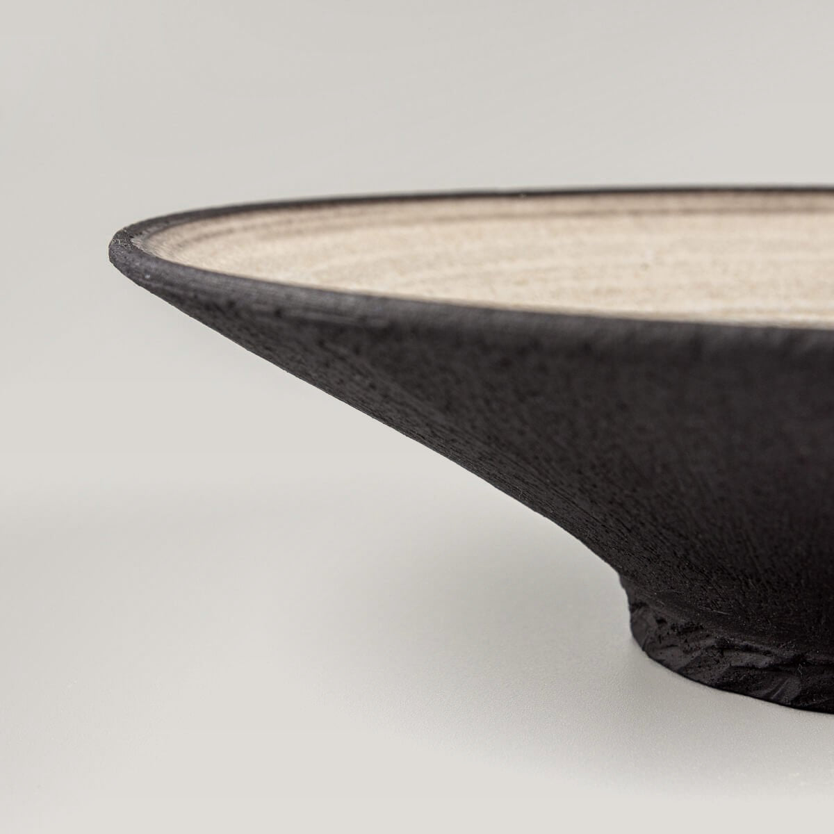 Wheel-thrown black stoneware plate with refined minimalist craftsmanship.