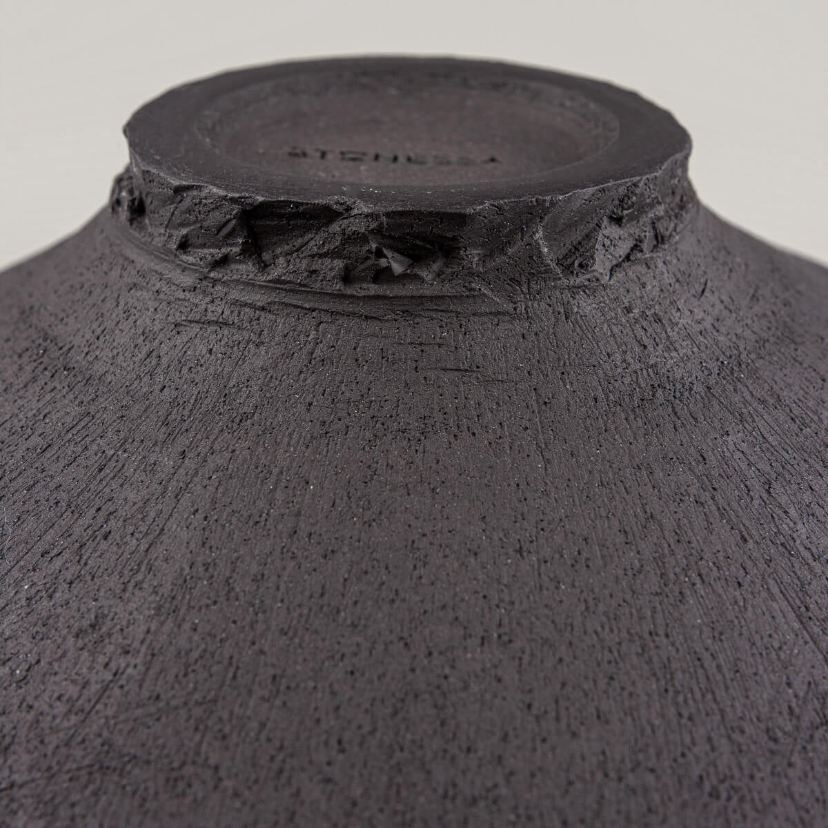 Foot detail with visible carving marks and natural ceramic finish.