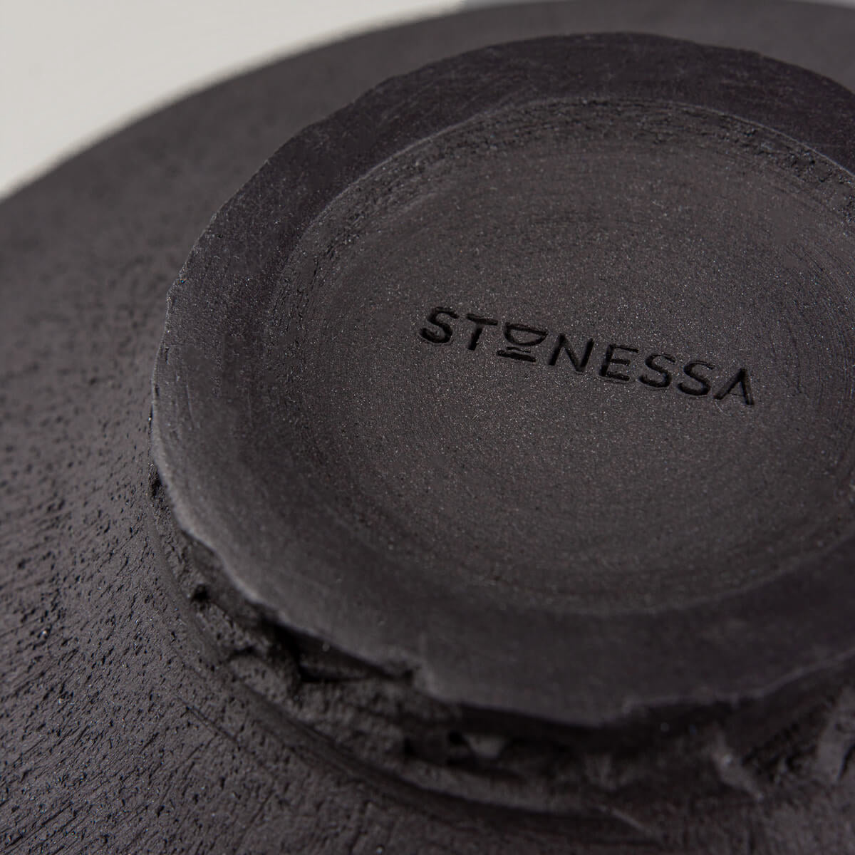 Hand-carved ceramic foot with textured dark clay and artisan signature.
