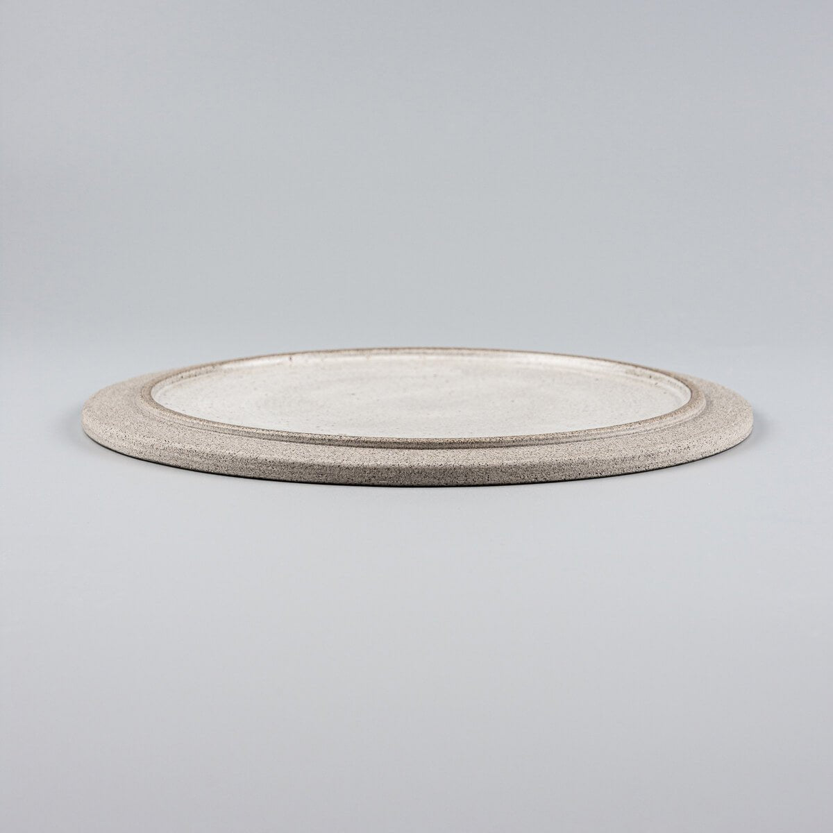 Side view of stackable handmade ceramic plate with flat design and elegant profile.