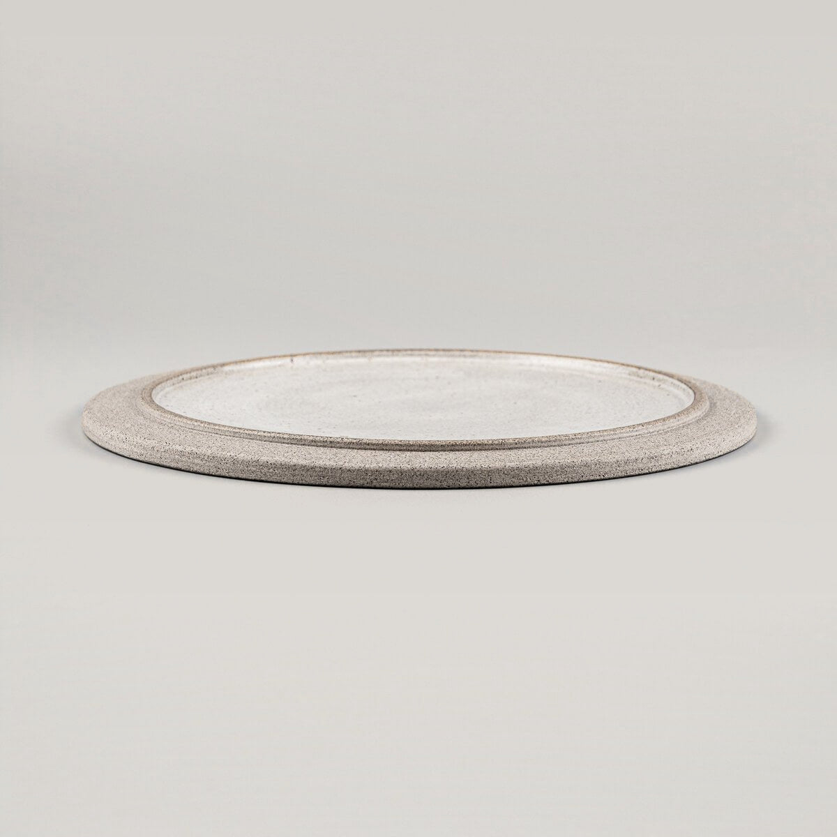 Side view of stackable handmade ceramic plate with flat design and elegant profile.