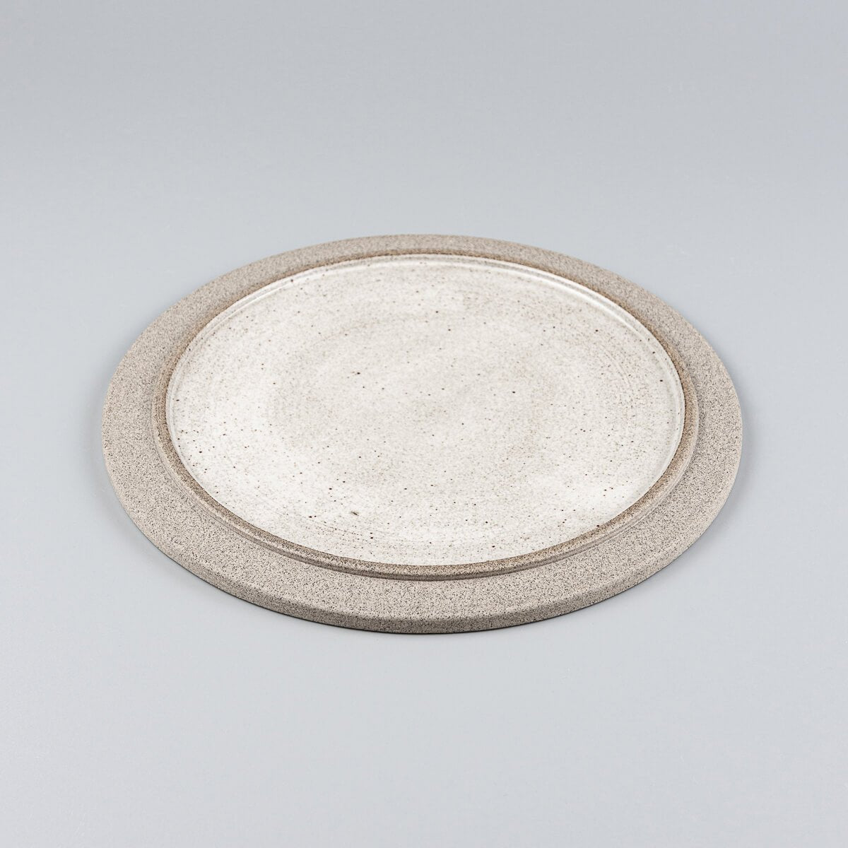 Minimalist ceramic plate in stoneware with contrasting glazed center and unglazed edge.