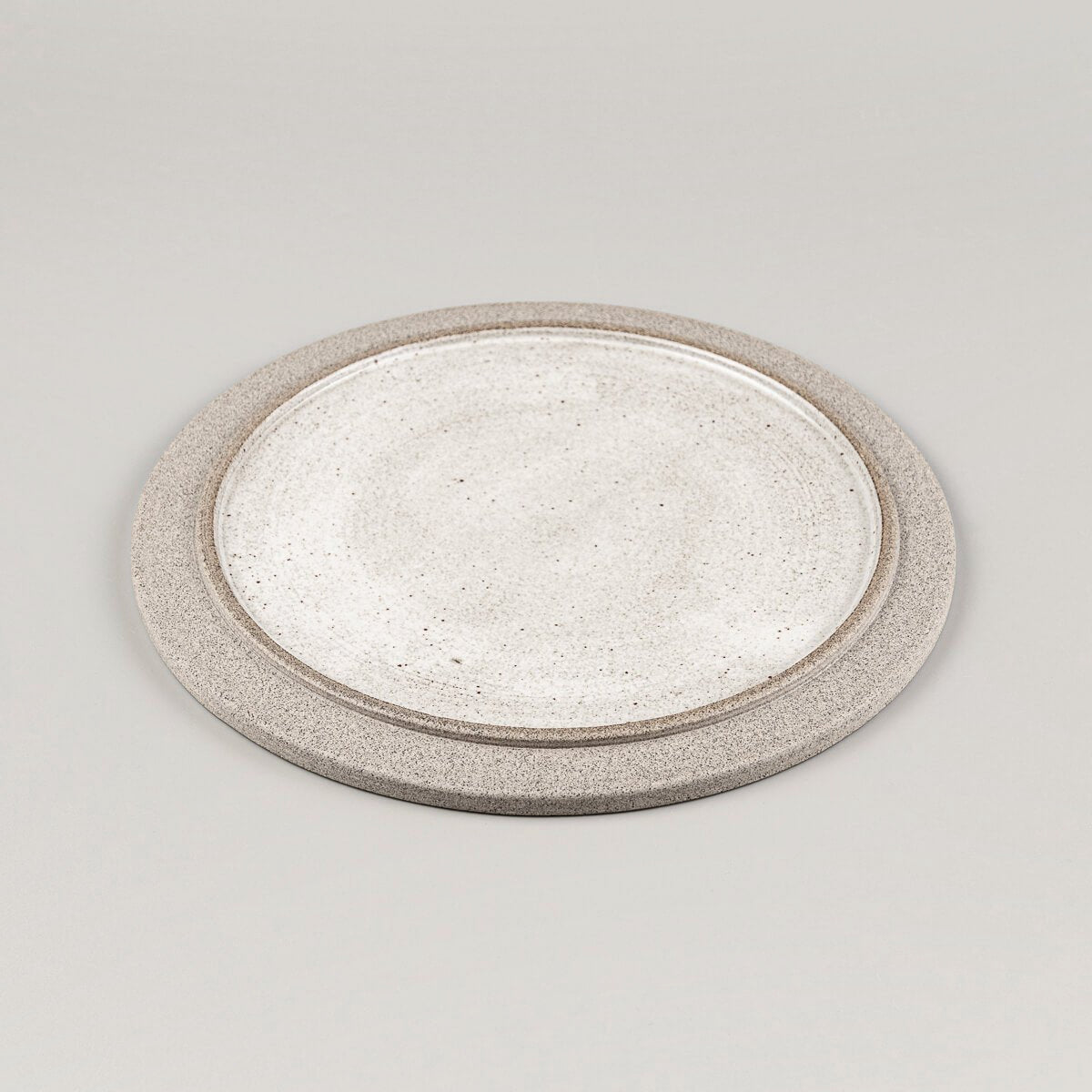 Minimalist ceramic plate in stoneware with contrasting glazed center and unglazed edge.