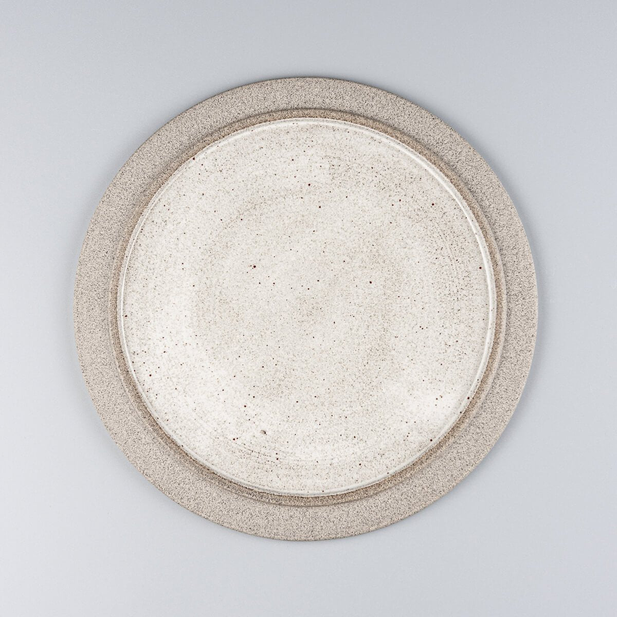 Flat handmade ceramic plate with white glossy glaze and natural stoneware rim for modern fine dining.