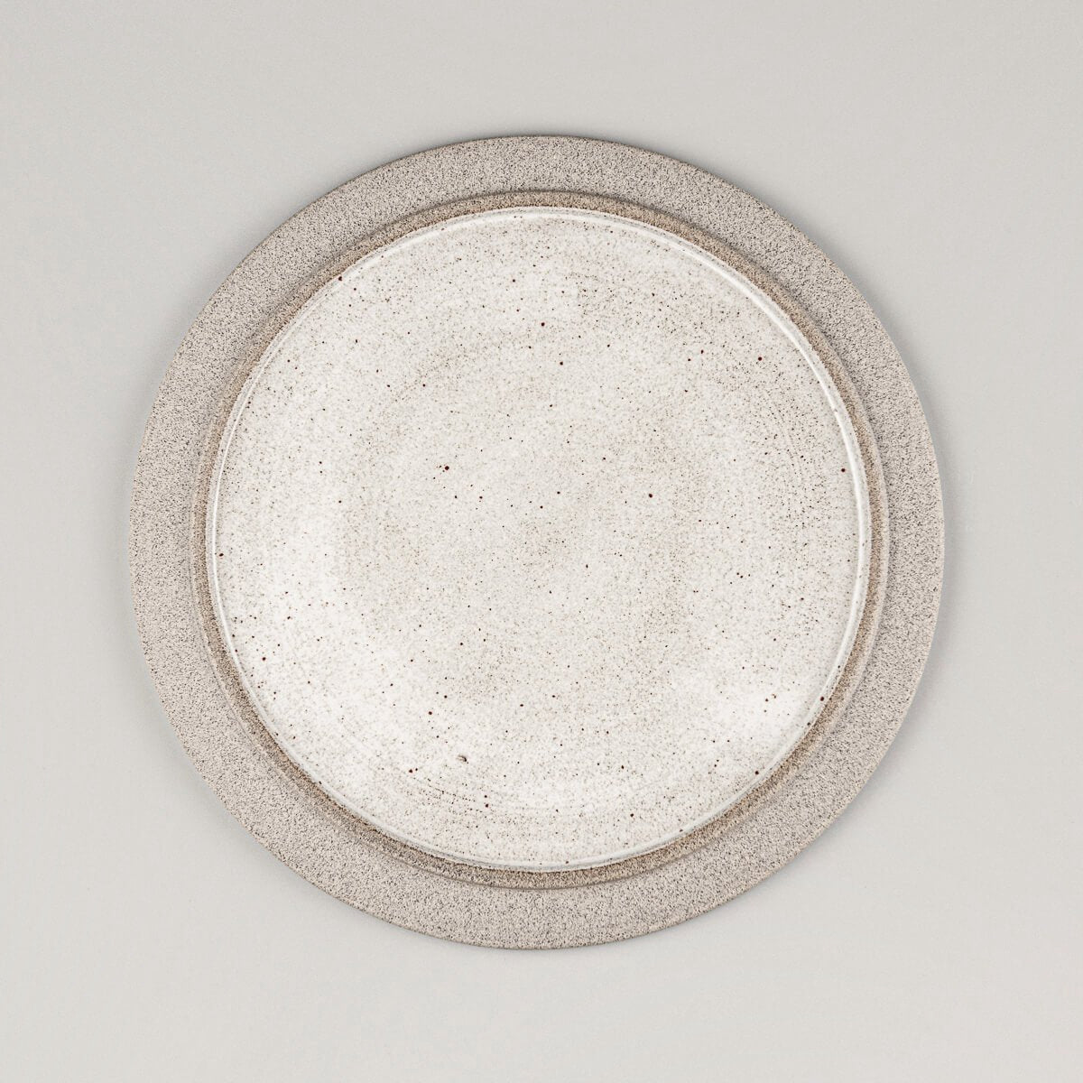 Flat handmade ceramic plate with white glossy glaze and natural stoneware rim for modern fine dining.