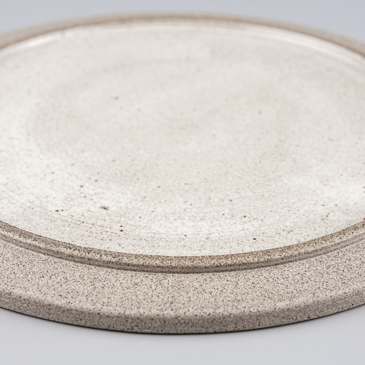 Detail of handmade ceramic plate with refined glaze work and natural texture.