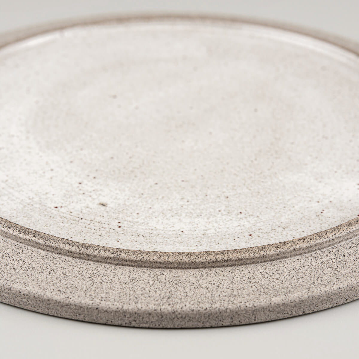 Detail of handmade ceramic plate with refined glaze work and natural texture.
