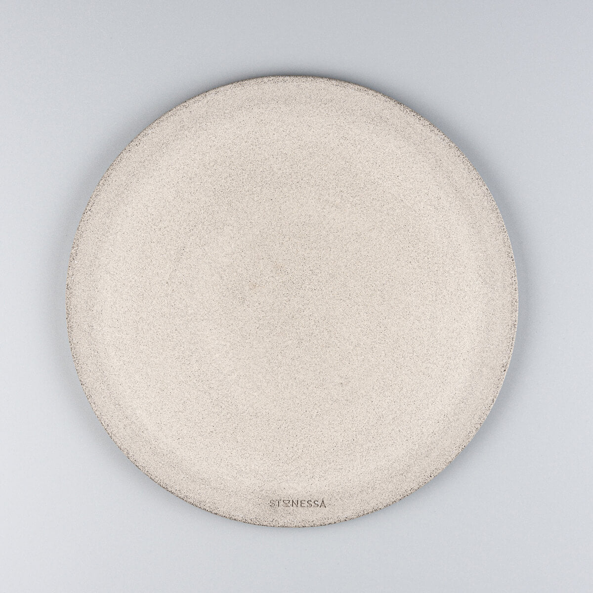 Underglazed bottom of handmade ceramic plate with visible footring and raw stoneware texture.