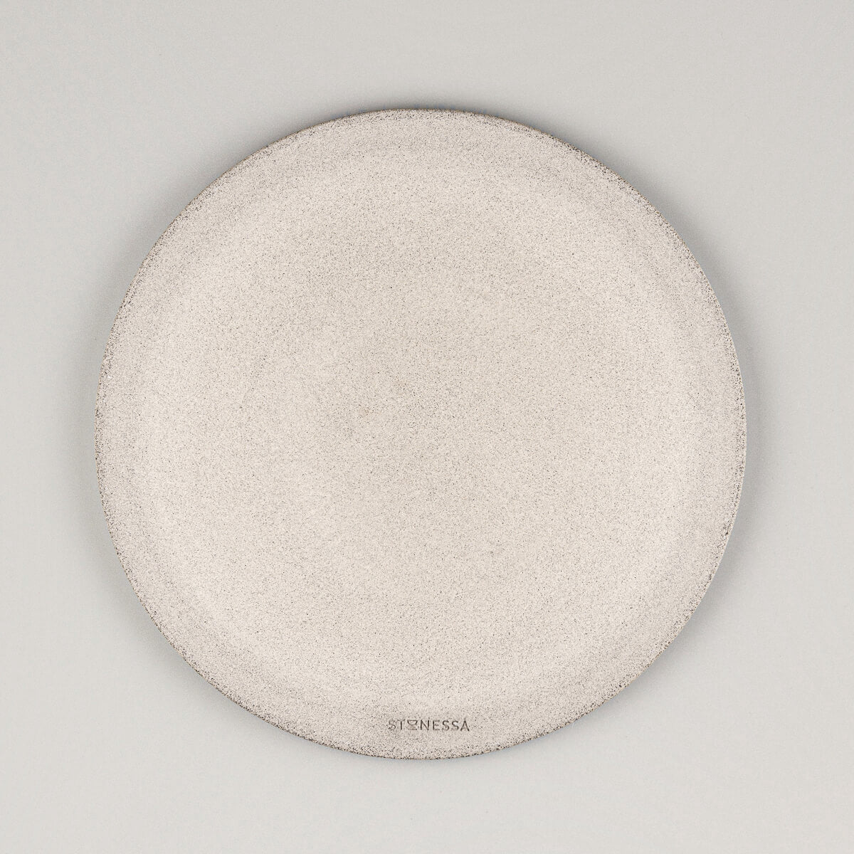 Underglazed bottom of handmade ceramic plate with visible footring and raw stoneware texture.