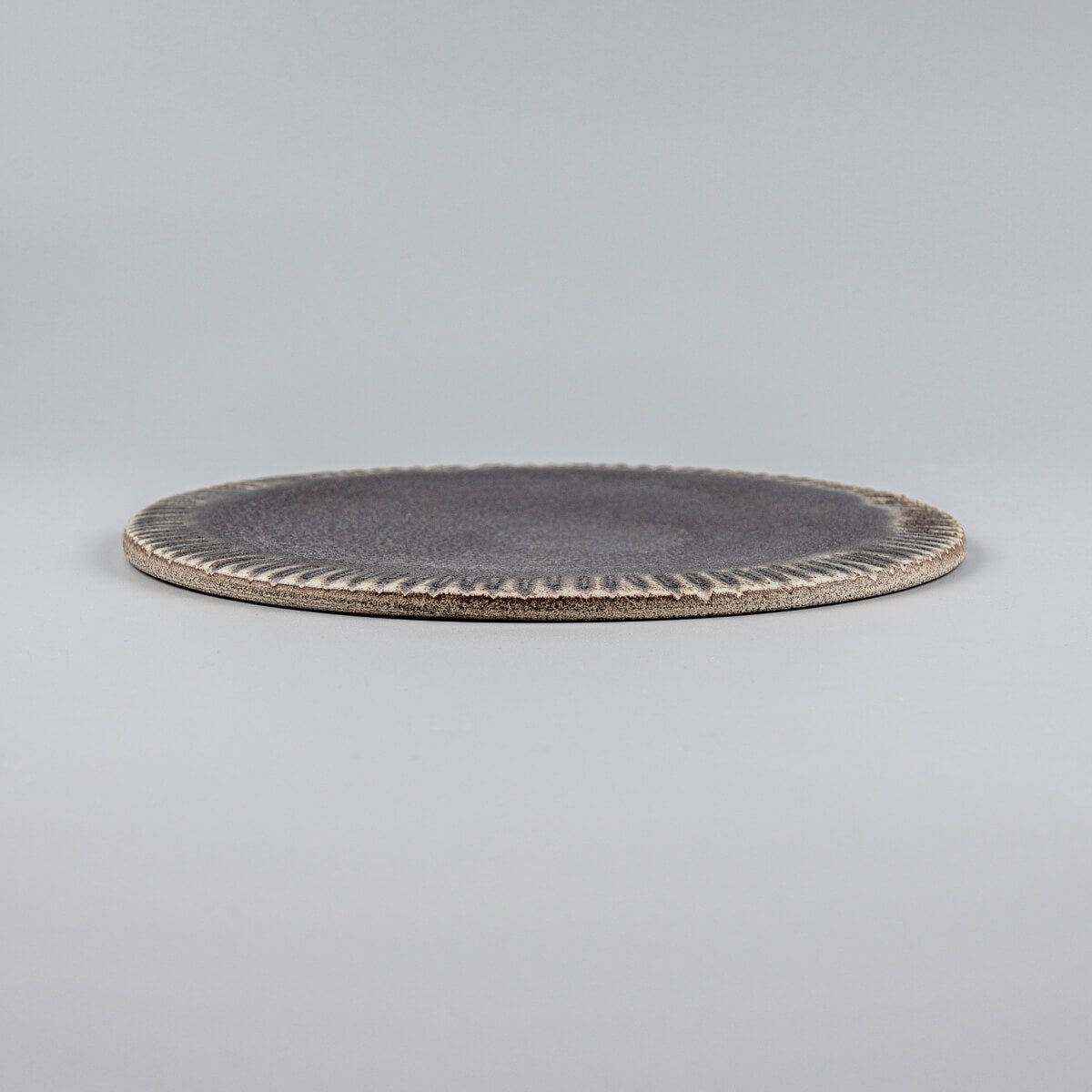Slim, stackable ceramic plate in matte dark glaze, perfect for dessert presentations.