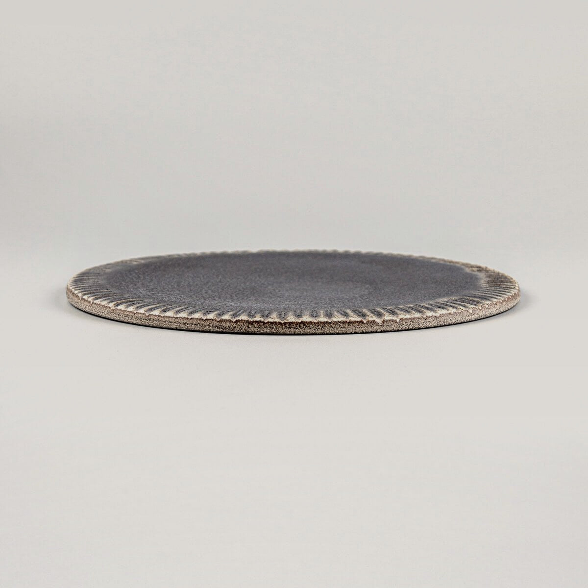 Slim, stackable ceramic plate in matte dark glaze, perfect for dessert presentations.
