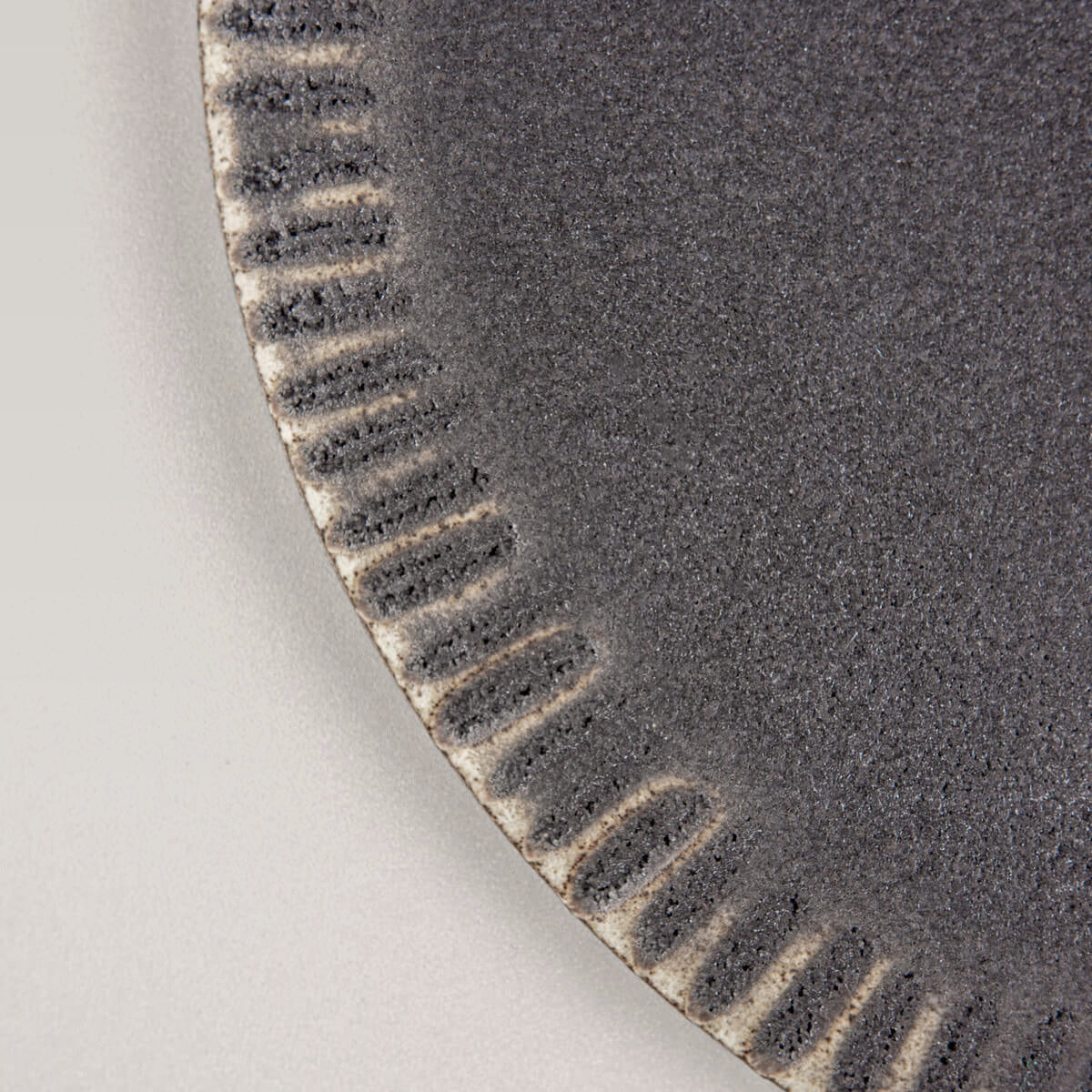 Close-up of textured rim on artisanal ceramic dessert plate for boutique hotel dining.