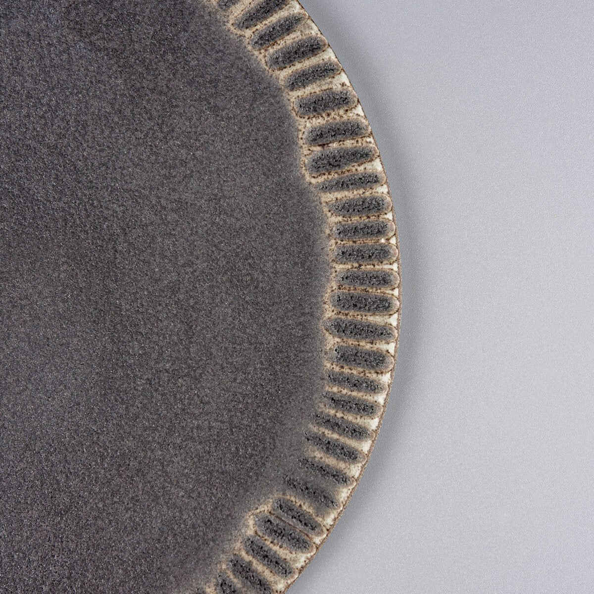 Side view of elegant ceramic serving plate with refined hand-tooled rim for fine dining.