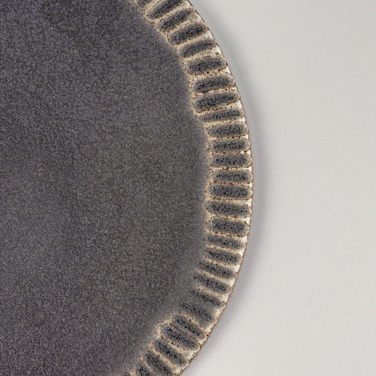 Side view of elegant ceramic serving plate with refined hand-tooled rim for fine dining.