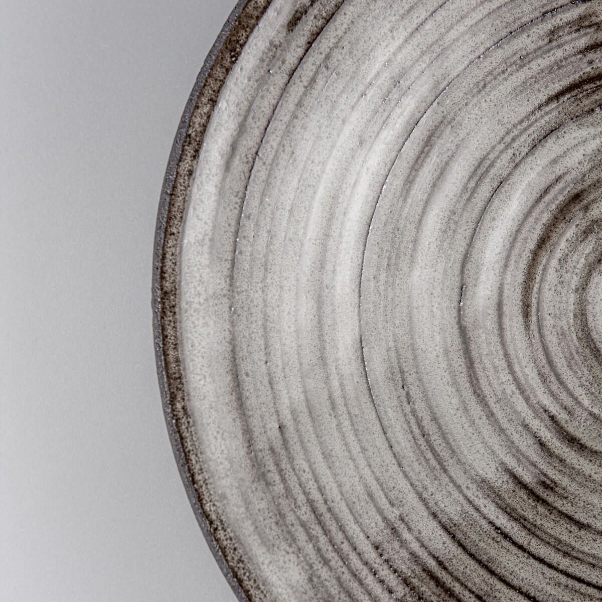 Close-up of handcrafted stoneware plate showing detailed gray glaze and precisely carved edges.