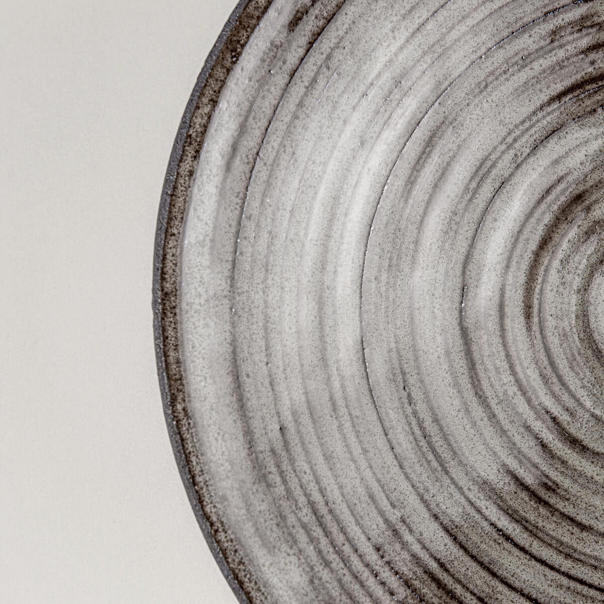 Close-up of handcrafted stoneware plate showing detailed gray glaze and precisely carved edges.