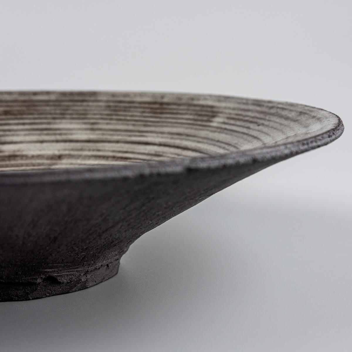Close-up of the carved base on luxury stoneware plate for refined culinary service.