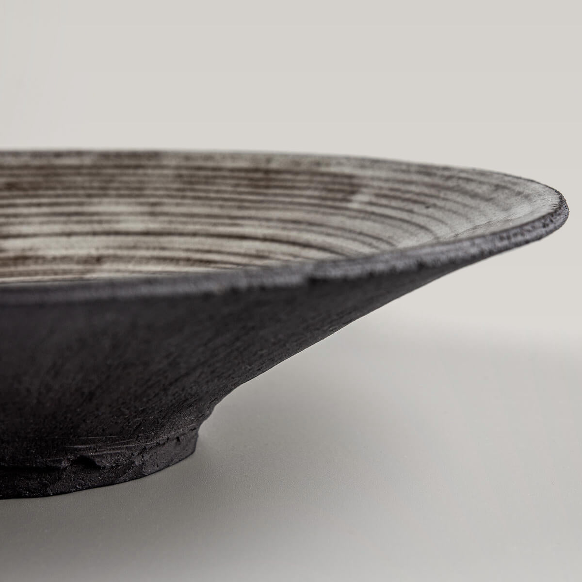 Close-up of the carved base on luxury stoneware plate for refined culinary service.