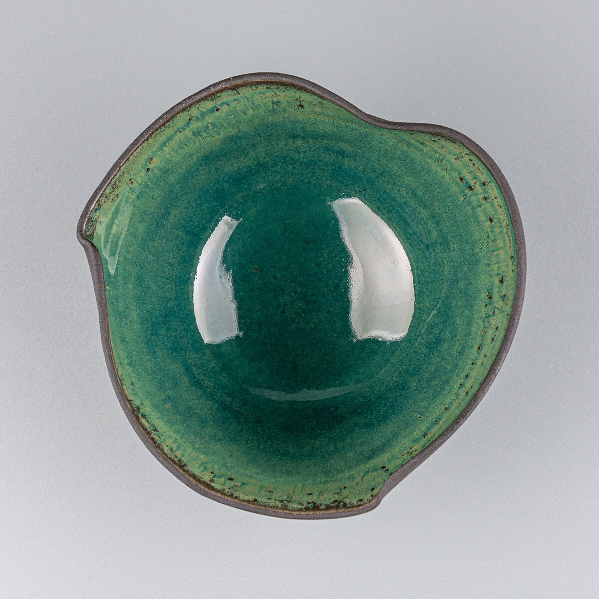 Top view of artisan-crafted bowl with black clay exterior and vivid green glazed interior.