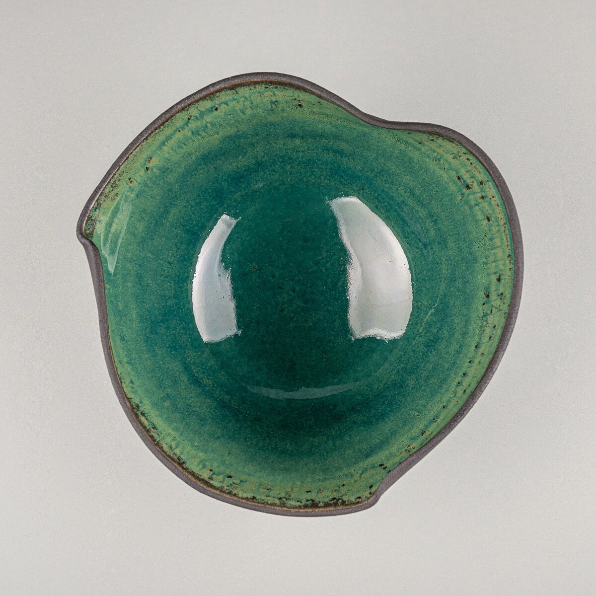 Top view of artisan-crafted bowl with black clay exterior and vivid green glazed interior.