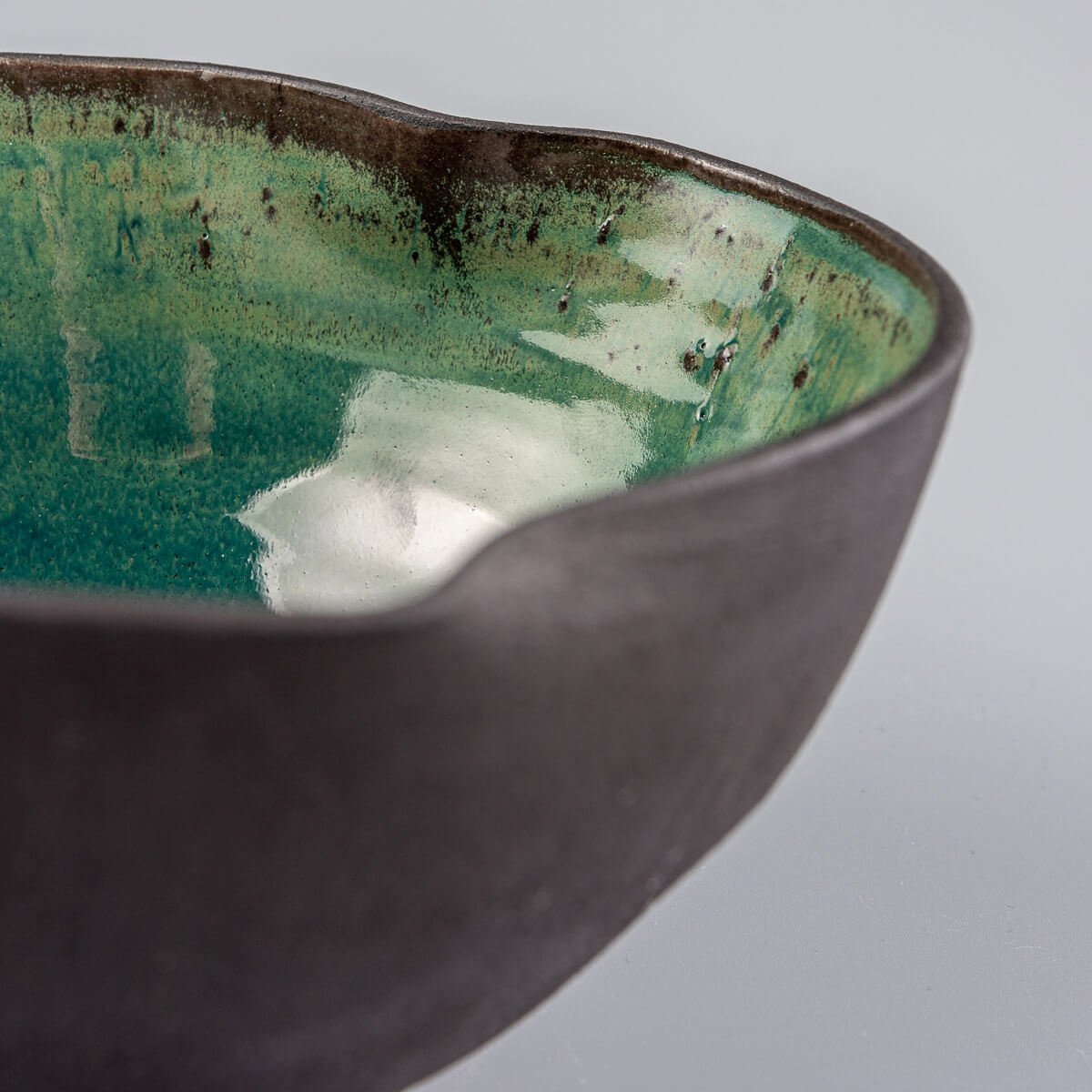 Side angle of stoneware bowl showing natural unglazed black clay texture.