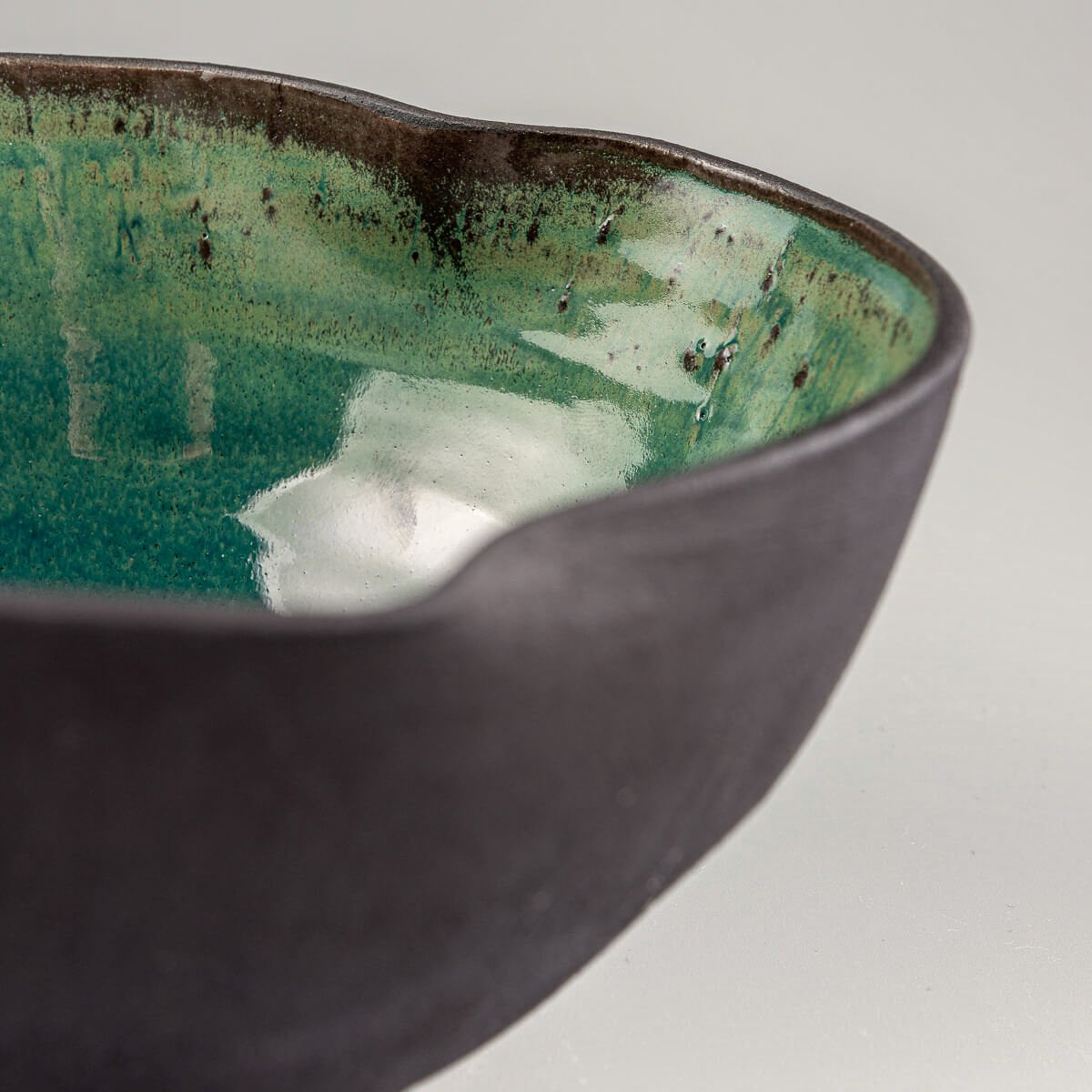 Side angle of stoneware bowl showing natural unglazed black clay texture.