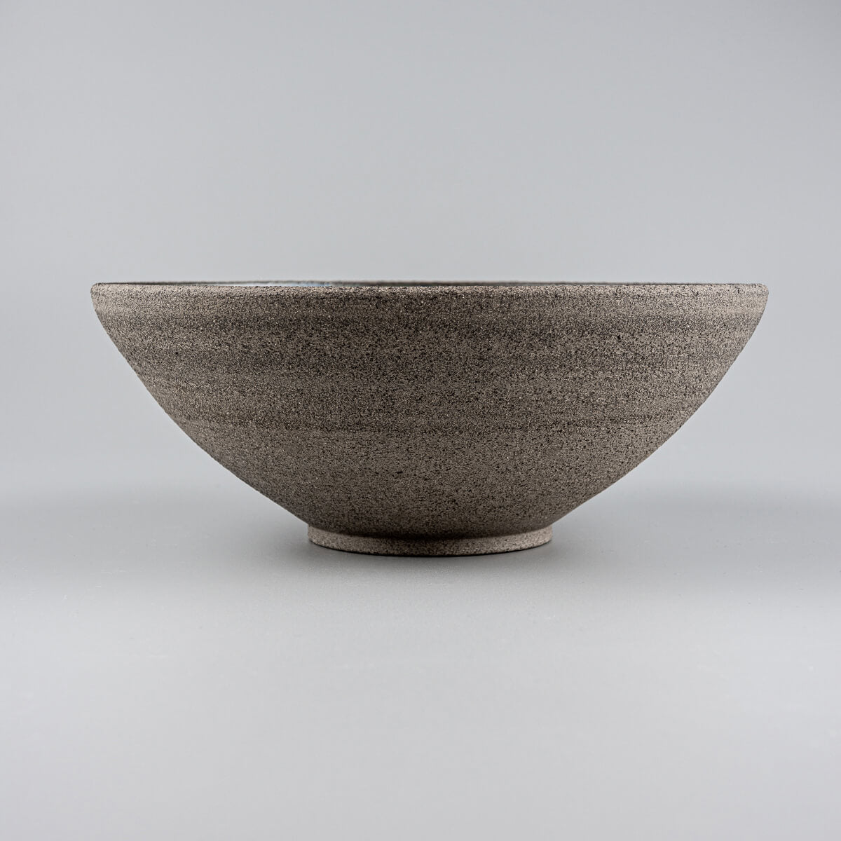 Profile view of handmade bowl highlighting sloped walls and natural clay texture.