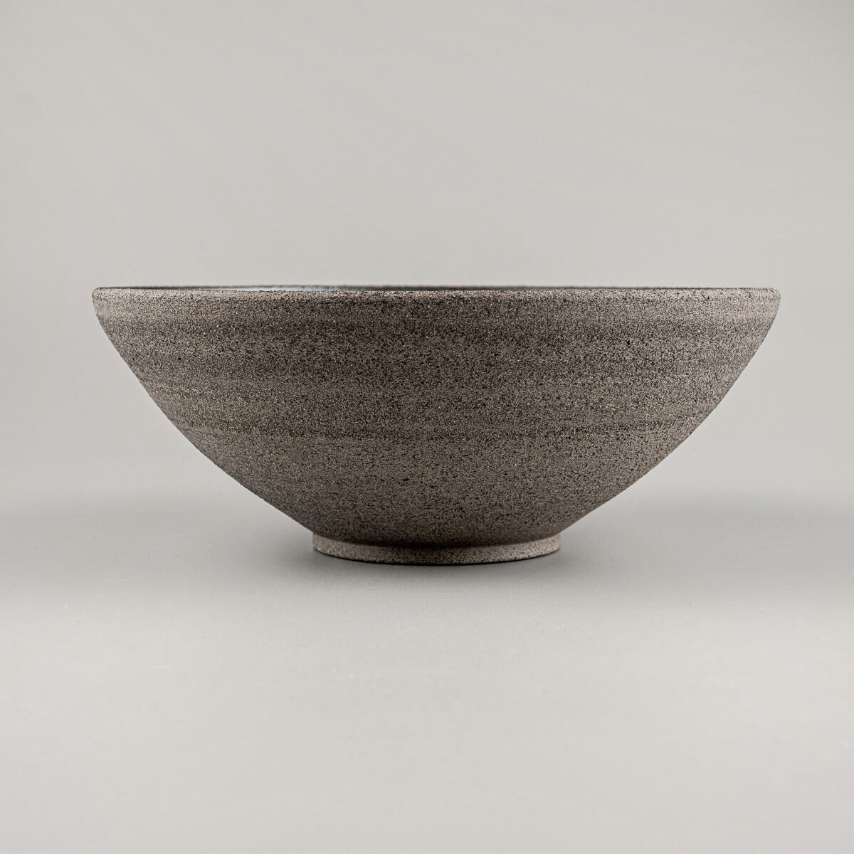 Profile view of handmade bowl highlighting sloped walls and natural clay texture.