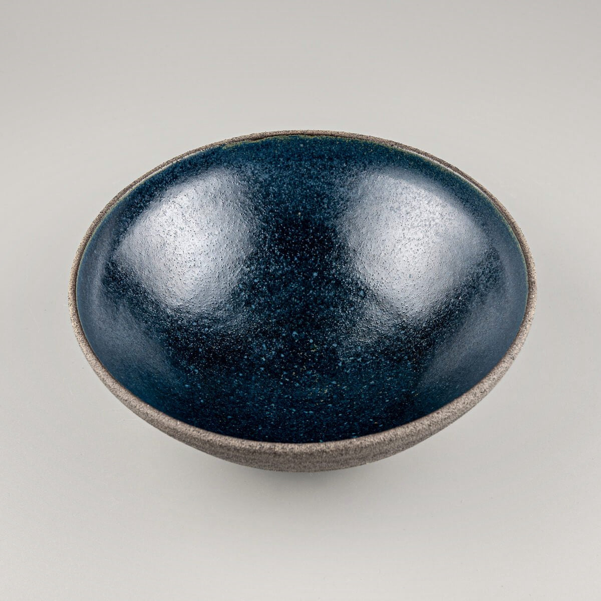 Angled front view of artisan-crafted bowl with contrasting raw clay surface and smooth glazed inside.